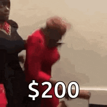 a man is holding a woman in a red dress and says `` $ 200 '' while another man stands behind her .