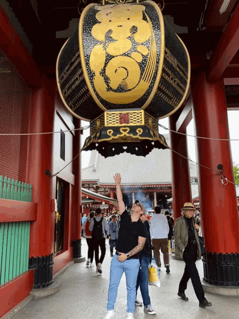 a man in a black shirt stands in front of a large lantern with chinese writing