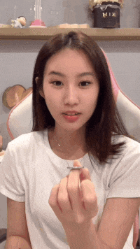 a woman wearing a white t-shirt is holding a small object in her hand