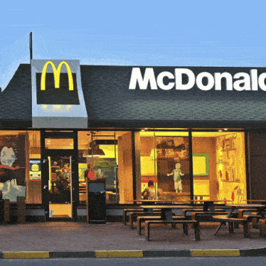 the outside of a mcdonald 's restaurant with tables and chairs outside
