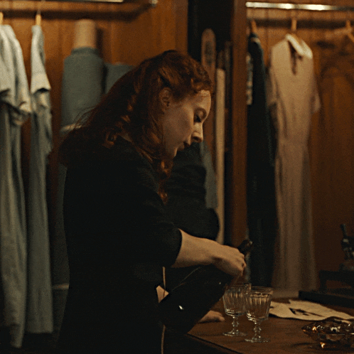 a woman is pouring a bottle of wine into a glass on a table