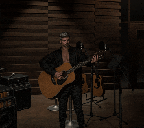 a man playing an acoustic guitar in front of a microphone that says fender on it