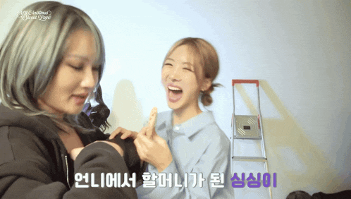 two girls are laughing in front of a sign that says christmas 's sweet love