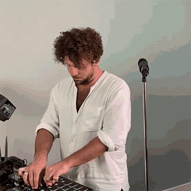 a man in a white shirt is playing a mixer in front of a microphone