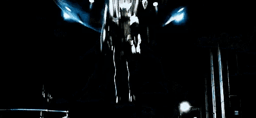 a man in a superhero costume is standing in the middle of a city street at night .
