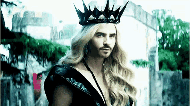 a man with long blonde hair and a crown is wearing a black dress .