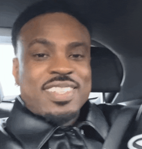 a man with a beard is smiling while sitting in a car