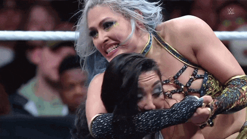 two women are wrestling in a ring with a w logo on the bottom