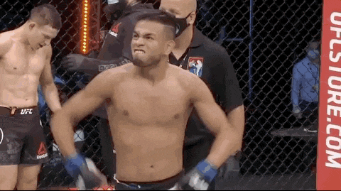 a man without a shirt is standing in a boxing ring with a referee .