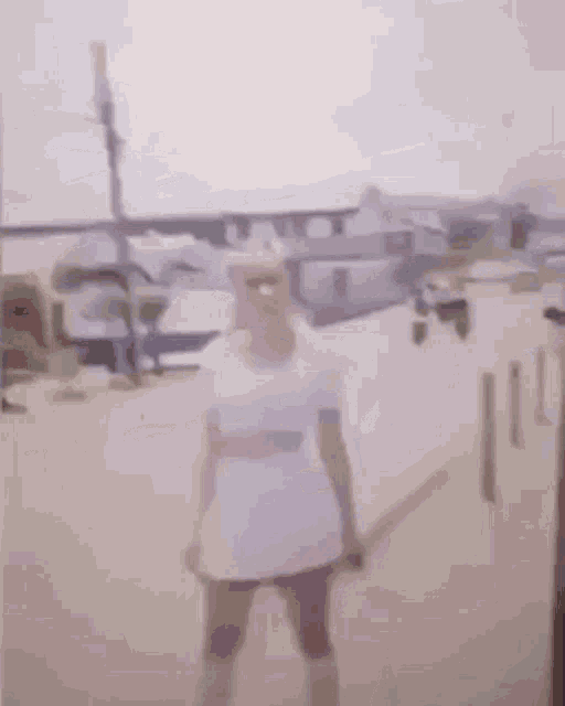 a woman in a white dress is standing on the side of a street holding a pole .