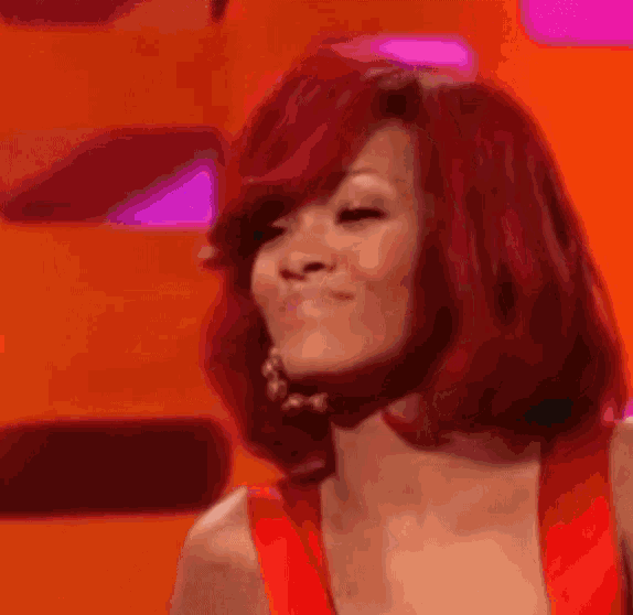 a woman with red hair and hoop earrings is smiling and making a funny face .