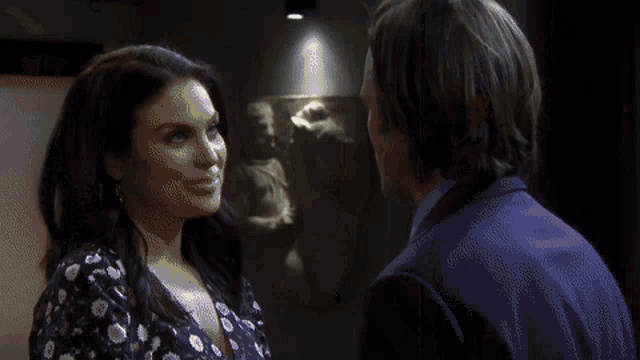 a man and a woman are looking at each other in front of a painting