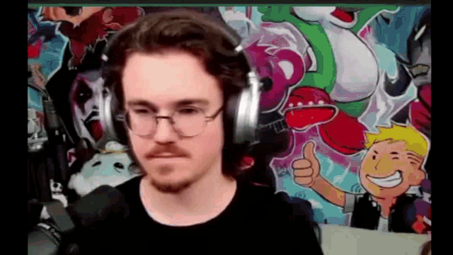 a man wearing headphones and glasses is giving a thumbs up in front of a cartoon character .