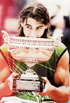 a man in a green shirt is holding a trophy with his mouth