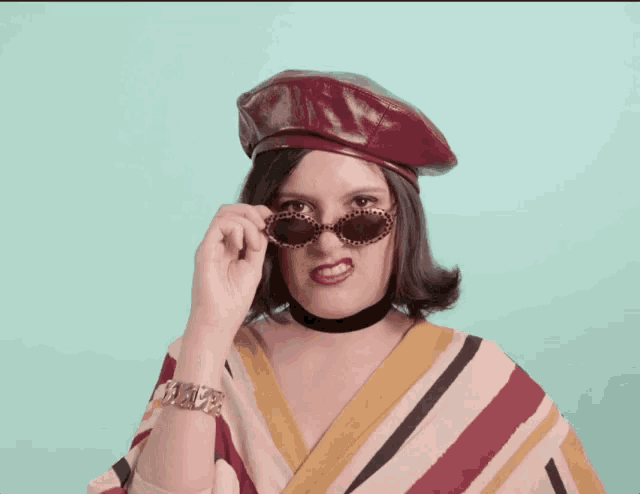 a woman wearing a beret and sunglasses is making a face