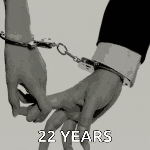 a man and woman are holding hands with handcuffs on their wrists .
