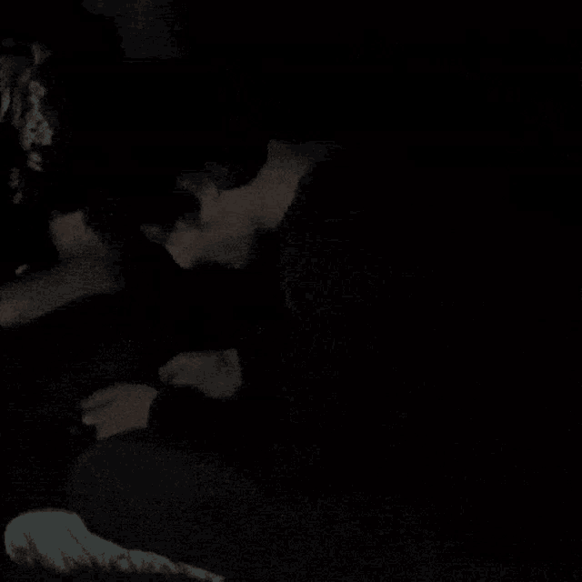 a man in a red sweater is sitting in the dark