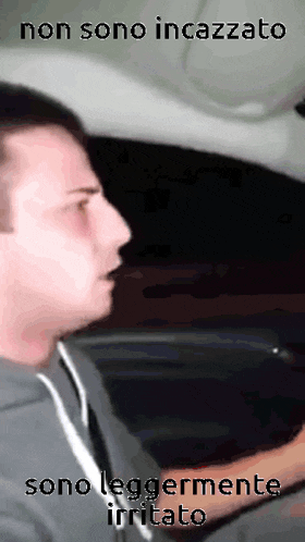 a man is driving a car with the words non sono incazzato sono leggermente irritato on the bottom .