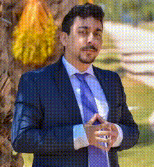 a man in a suit and tie is standing in front of a tree