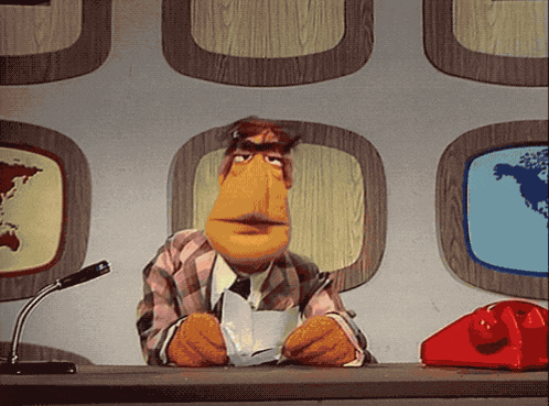 a puppet is sitting at a desk with a red telephone