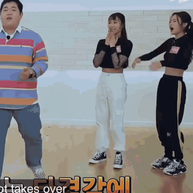 a man in a striped shirt is standing next to two girls with the words " it takes over " on the bottom right