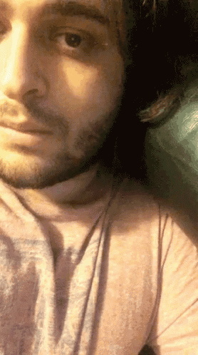 a close up of a man 's face with a beard wearing a pink shirt