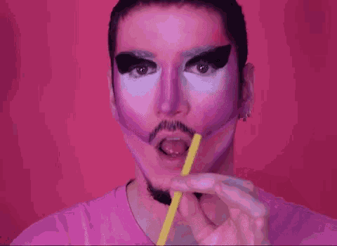 a man with pink makeup on his face is drinking through a straw