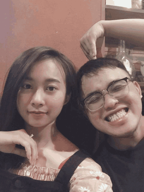a man and a woman are posing for a picture and the man has glasses