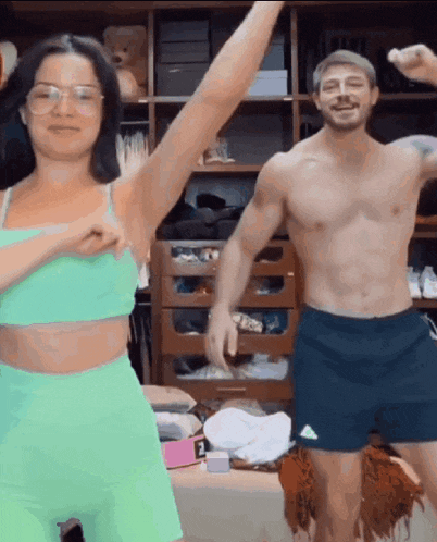 a shirtless man and a woman are dancing in front of a closet