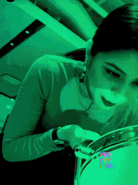 a woman playing a drum with a green background that says " well spot " on it