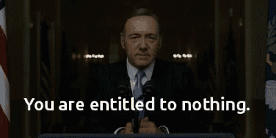 a man in a suit and tie stands at a podium with the words " you are entitled to nothing " above him