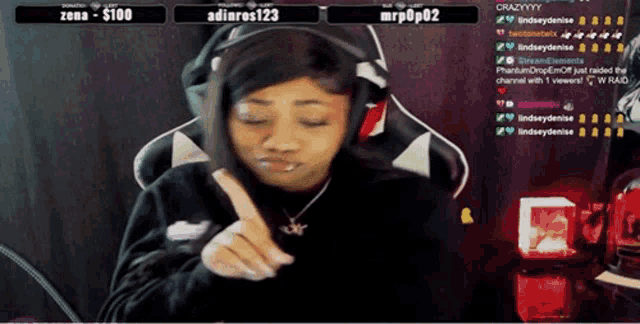 a woman wearing headphones and a necklace is playing a video game on a stream