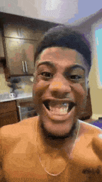 a man without a shirt is smiling with his mouth open