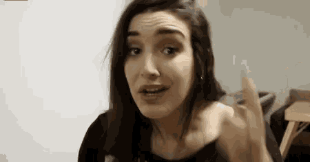a woman is making a funny face and pointing her finger at the camera .