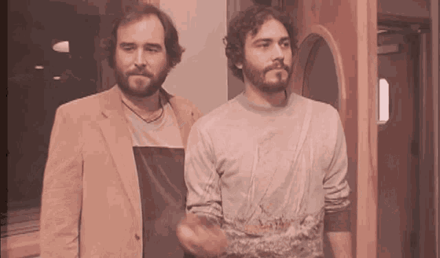 two men are standing next to each other and one has a beard
