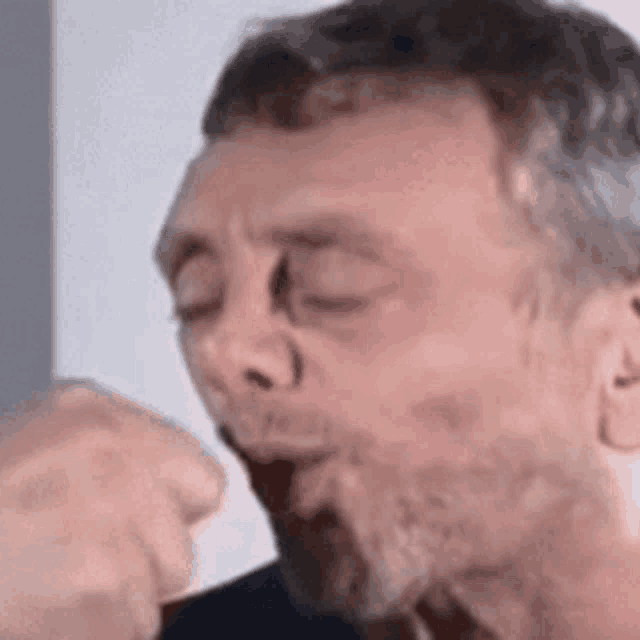 a man with a beard is blowing a kiss with his hand .