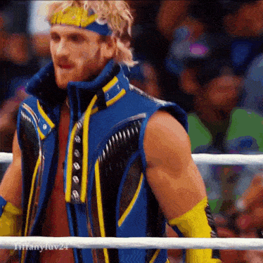 a wrestler in a blue and yellow outfit is standing in a ring with tiffanyluv24 written on the bottom right