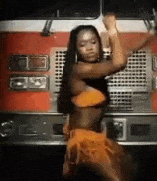 a woman in a bikini is dancing in front of a red truck .