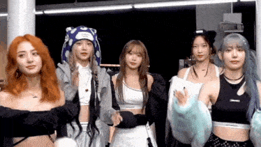 a group of young women are standing next to each other in a room and looking at the camera .