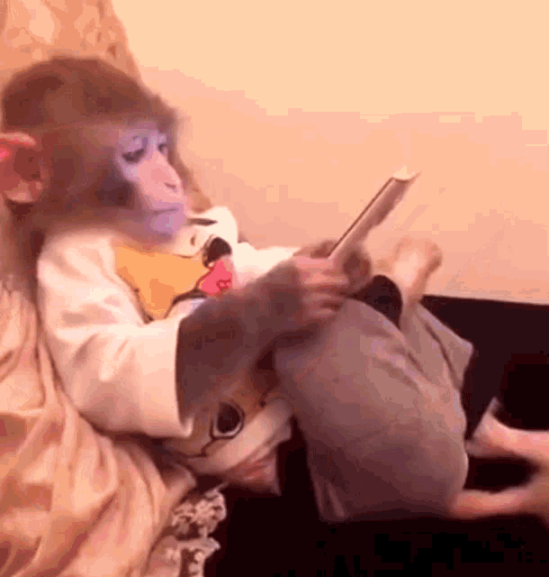 Macaco de pijamas deitado na cama usando um celular.