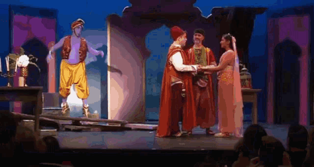 a group of people standing on a stage with a man in a turban standing behind them