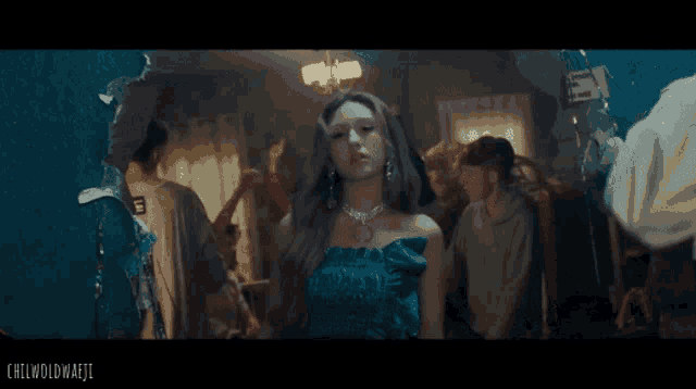 a woman in a blue dress is standing in a crowd of people and the words chilwoldmajii are on the bottom