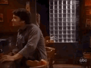 a woman is talking to a man in a dark room with a abc logo on the bottom of the screen .