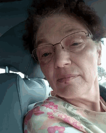 an older woman wearing glasses and a floral shirt is sitting in the back seat of a car