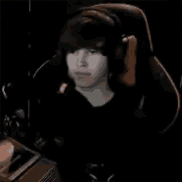 a young boy is sitting in a gaming chair wearing headphones and making a funny face .