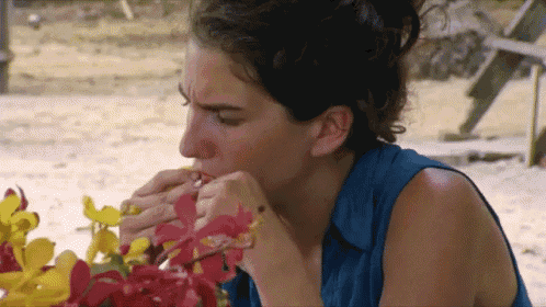 a woman in a blue shirt is eating flowers