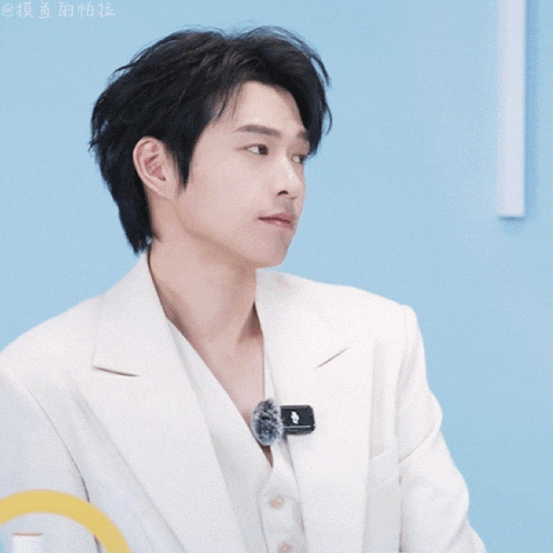 a man in a white suit has a black pin on his collar