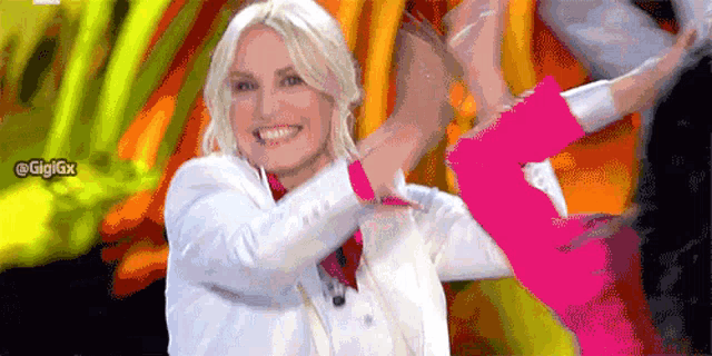 a woman in a white jacket and pink sleeves is smiling and dancing