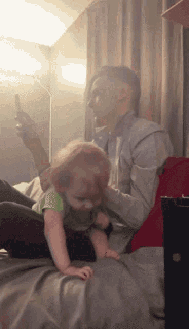 a man is playing with a baby who is crawling on his lap