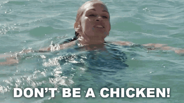 a woman is swimming in the ocean with the words " do n't be a chicken " written on the bottom